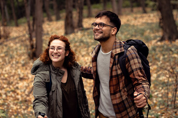 Two young hikers with backpack walking in forest.