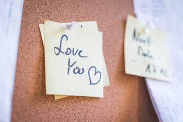 “Love you” note for loving couple, pinned on cork board