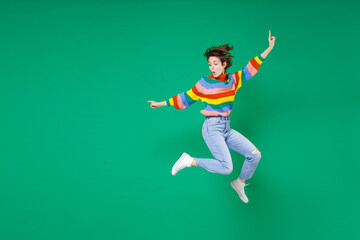 Fototapeta na wymiar Full length side view of amazed young brunette woman 20s years old in casual colorful sweater jumping spreading hands pointing fingers aside isolated on bright green color background studio portrait.