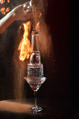 sambuca alcoholic cocktail with a tower of glasses and fire on a dark background