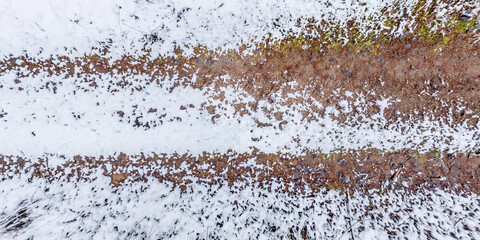 panorama view from above on texture of snow covered gravel dirt road in the forest