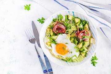 Ketogenic, paleo diet. Fried egg, prosciutto, avocado and fresh salad.  Keto breakfast. Brunch.  Top view, overhead, flat lay
