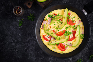Keto breakfast. Omelette with ham,  tomatoes and avocado on grey table. Italian frittata. Keto, ketogenic lunch. Top view, overhead, copy space