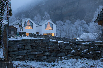 Modern with house with large windows surronded by mountain, snow and fog
