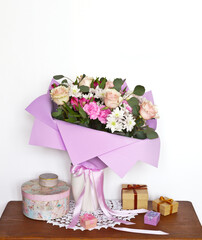 Romantic surprise for holiday: a bouquet of beautiful fresh rose flowers and boxes with gifts on a wooden table. Celebrating Mother's Day, Valentine's Day, March 8, Birthday or Family Anniversary