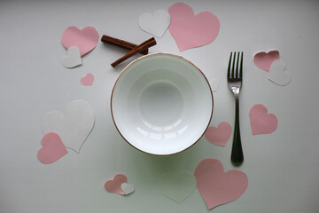 Plate with a fork on a white background. Valentine's Day. Paper hearts. Cinnamon sticks.