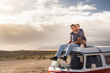 Young love couple sit down on a roof van enjoy travel lifestyle and holiday vacation together -...