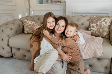 Fototapeta na wymiar Happy family. Mom hugs son and daughter, love. Cheerful joyful emotions on the face of a woman, a boy and a girl. Family leisure