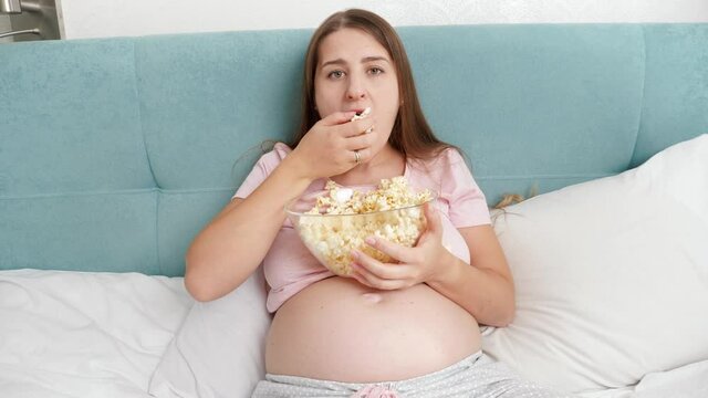 Portrait of funny woman feeling hungry eating popcorn and grabbing it with hand from big bowl. Concept of bulimia and overeating