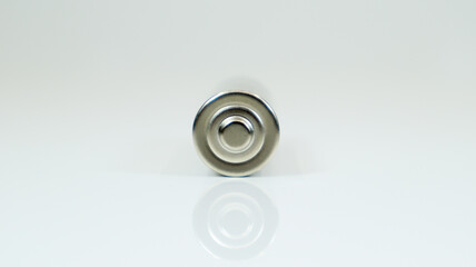AA alkaline rechargeable battery on white glossy background with reflection. Close one empty...