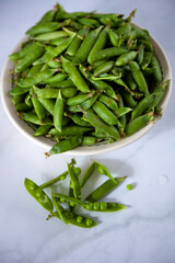 Peas. Green pea pods in a plate on a white table. Harvest. Healthy food close-up. Copy space.