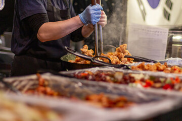 Hands of a person with a ready to eat food box or tasting in a brown cardboard box at a street food market. Brick Lane, London