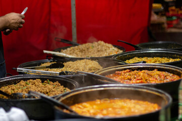 Street food, barbecuing on a hot grill with fire and smoke, thai food, vegetables and meat cooked for taking out. Brick Lane Food Market