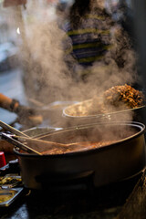 Street food, barbecuing on a hot grill with fire and smoke, thai food, vegetables and meat cooked for taking out. Brick Lane Food Market