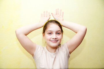Happy ten years old adorable girl in   beige t-shirt on yellow studio background