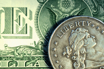 Close up one Dollar bill and coin with description: Liberty.