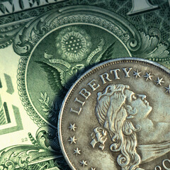Close up one Dollar bill and coin with description: Liberty as symbol: America - the land of opportunities and freedom.