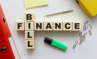 Wooden cubes with words BILL FINANCE on the office desk. Folder and other office supplies.