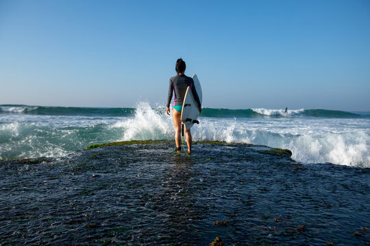 Woman surfer with surfboard going to surf at seaside