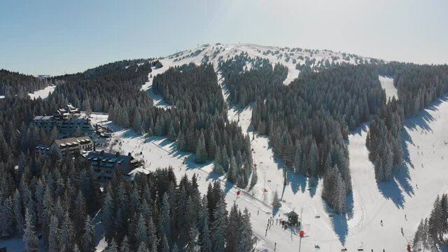Aerial: Kopaonik Mountain ski resort center in Serbia, covered in snow, Pancic peak, Pancicev vrh, Raska, Sunny day in winter