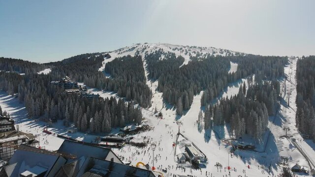 Aerial: Kopaonik Mountain ski resort center in Serbia, covered in snow, Pancic peak, Pancicev vrh, Raska, Sunny day in winter