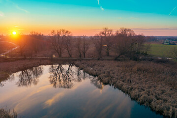 Sunset over the countryside. A beautiful reflection of trees and sky in a serene evening lake. Natural landscape. Aerial view from drone