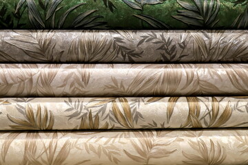 Rolled up rolls of vinyl wallpaper. Different textures and colors, as background. Green, beige,...