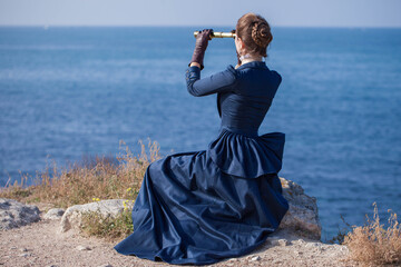 Romantic young beautiful lady looks at spyglass seascape. Vintage style. Steampunk concept. - obrazy, fototapety, plakaty