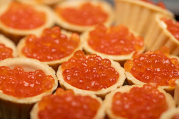 Tartlets with salmon caviar on a platter. Close-up, selective focus.