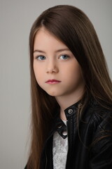 portrait of a girl child with beautiful hair in a black leather jacket on a white background