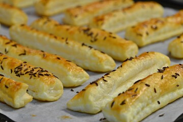 Baked salty sticks with salt and cumin. Golden baked savory pastry. Home baking appetizers. Crispy savory pastry on a baking sheet.