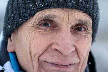Outdoor close portrait of senior man wearing warm knitted cap in winter season.