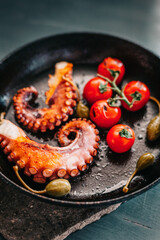 Octopus tentacles cooked in fried pan with cherry tomatoes