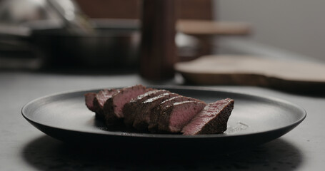 sliced beef steak on black plate on concrete countertop