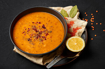 Ezogelin Soup in black bowl on dark slate table top. Turkish cuisine traditional dish with red lentils, bulgur and rice