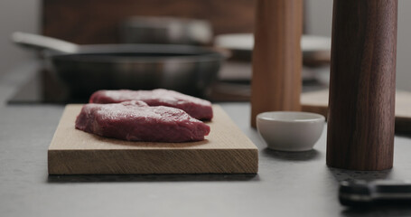 raw beef steak resting on oak board