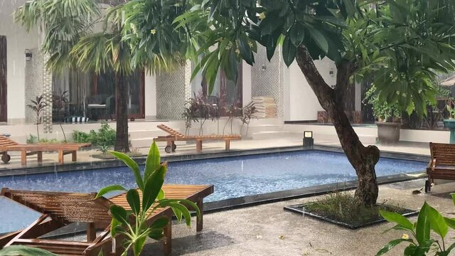 Tropical torrential rain falls in large drops on the pool water. A failed vacation in a heavenly place.