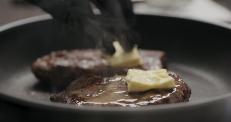 man rub butter on beef steak on nonstick pan