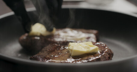 man rub butter on beef steak on nonstick pan