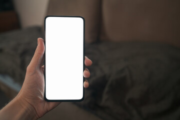 pov shot of man hand hold phone with white screen in dark interior