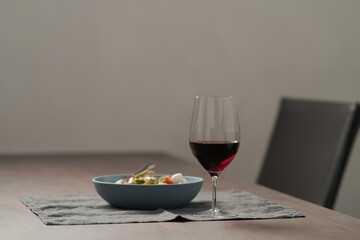Red wine in thin wine glass with pasta in blue bowl