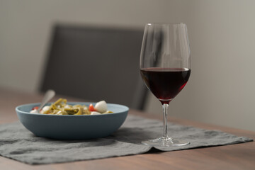 Red wine in thin wine glass with pasta in blue bowl