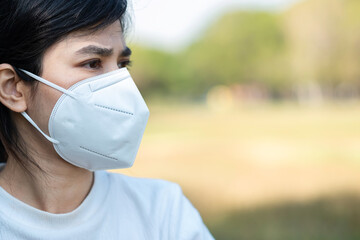 Woman wearing N95 respiratory medical face mask prevent coronavirus Disease (Covid-19) and pm2.5 (particulate matter). healthcare, New normal and air pollution concept, selective focus on Mask