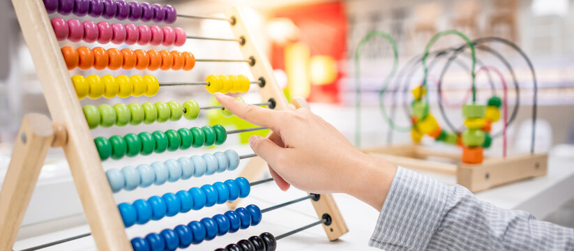 Male hand calculating with beads on wooden rainbow abacus for number calculation. Mathematics learning concept