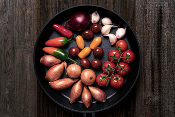 vegetables in a cast iron pan on wooden table,top view food.