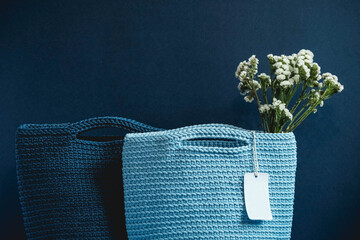 Two blue knitted handmade bag with flowers on a blue background. Copy, empty space for text