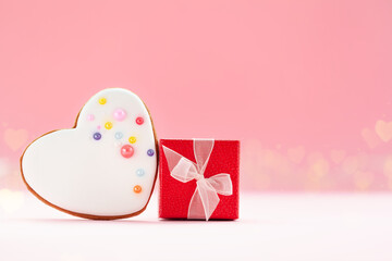 Red gift box with white heart shaped gingerbread for Valentines Day, Mother Day or Birthday on pink background