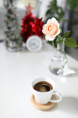 White coffee cup on white table decorated with rose and clock