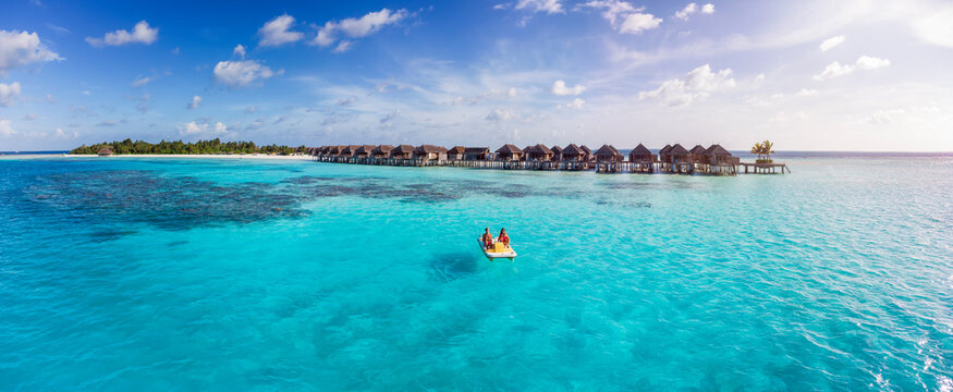 Aerial view of a happy family enjoying a pedalo boat ride over the turquoise ocean of the Maldives islands