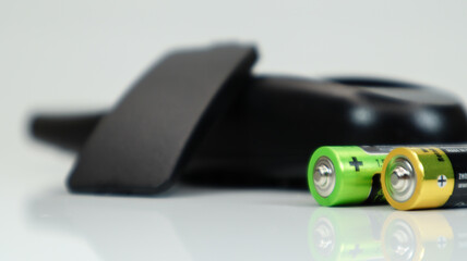 Black TV remote control with AAA alkaline batteries on a white background. Battery replacement, spare parts. Close up of the battery compartment of the remote control.